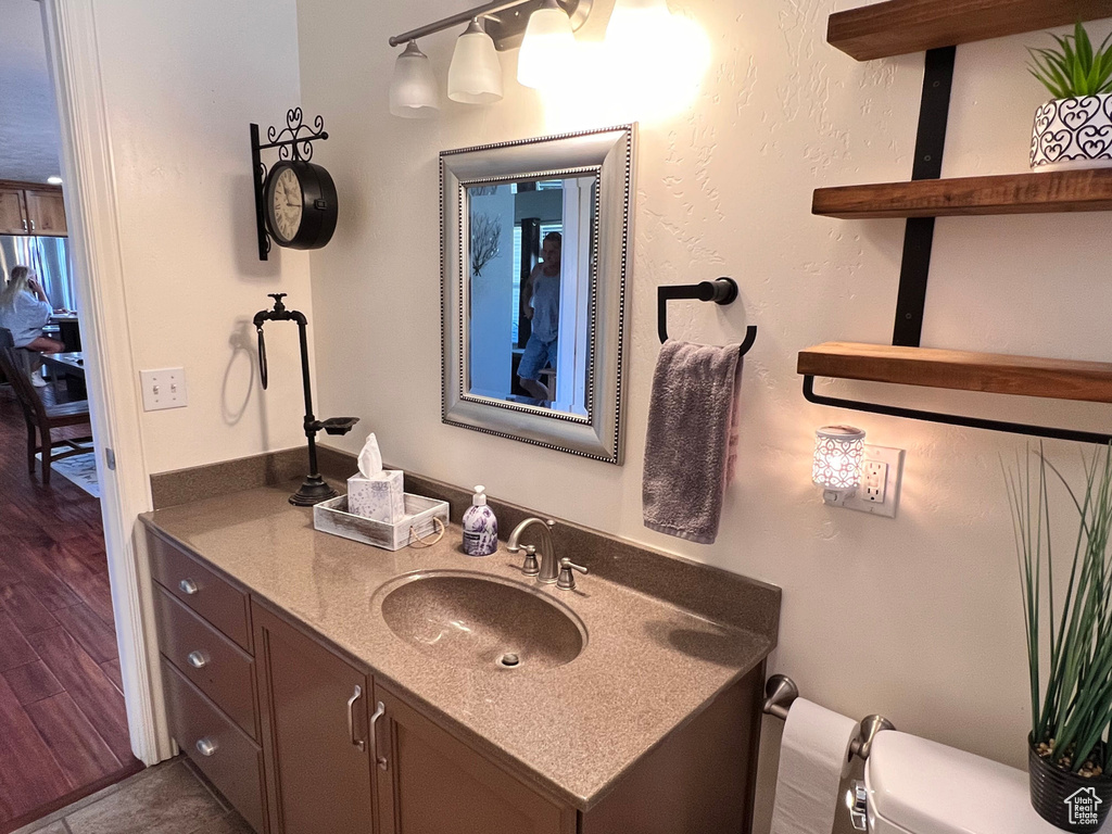 Bathroom with toilet, vanity, and wood finished floors
