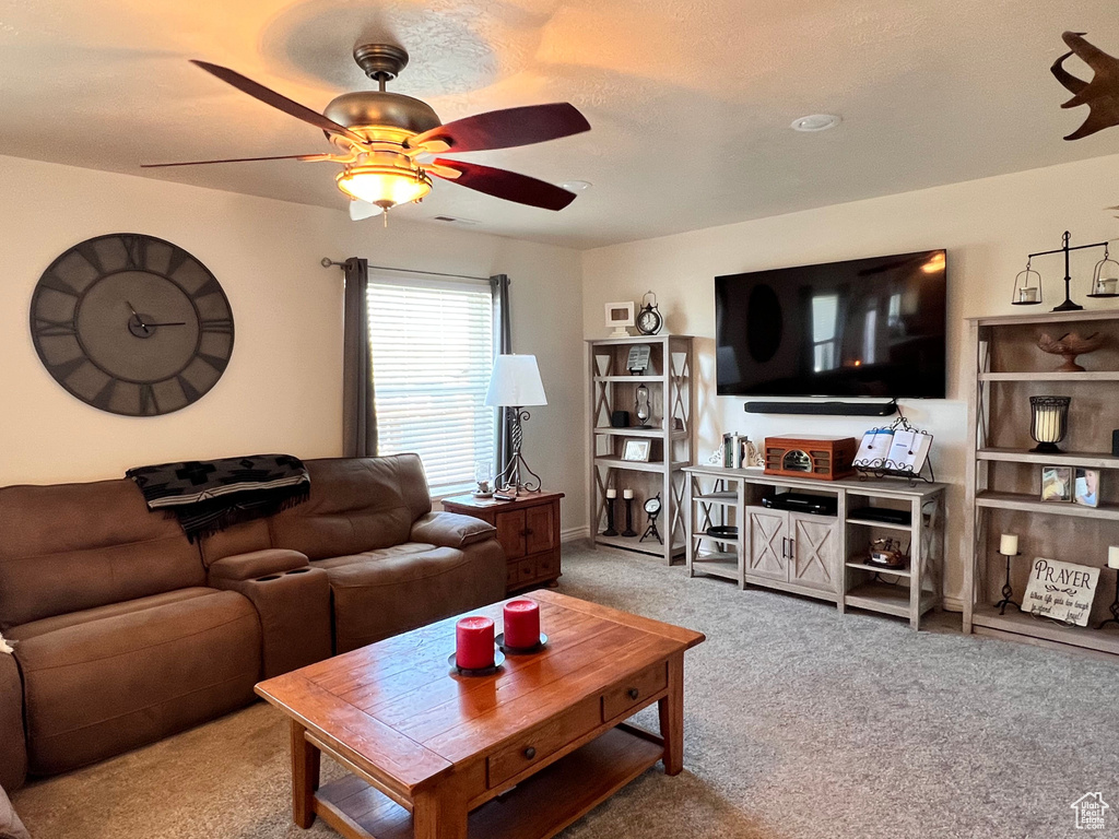 Carpeted living area with ceiling fan