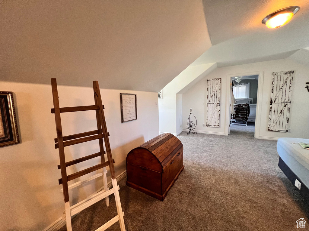 Carpeted bedroom featuring lofted ceiling and baseboards