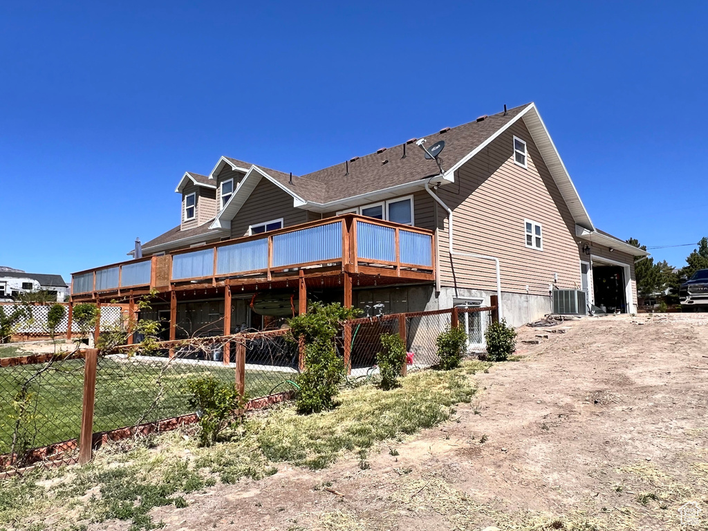 Back of house featuring central AC, a wooden deck, and a shingled roof