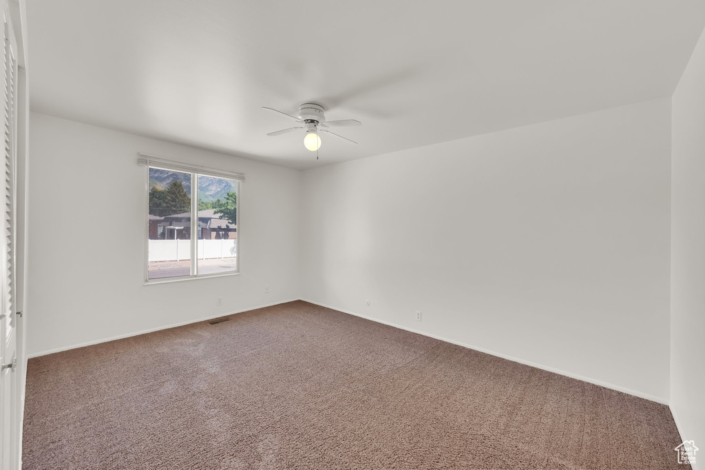 Spare room featuring a ceiling fan, carpet floors, and baseboards