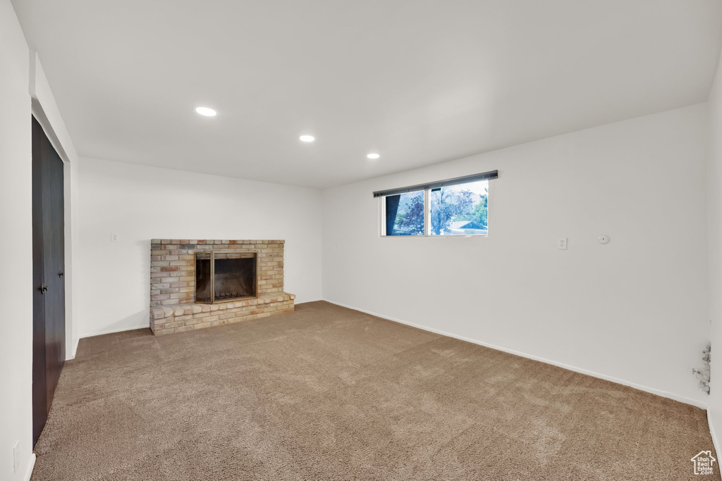 Unfurnished living room with carpet, recessed lighting, a fireplace, and baseboards