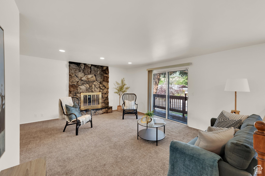 Carpeted living room featuring a stone fireplace and recessed lighting