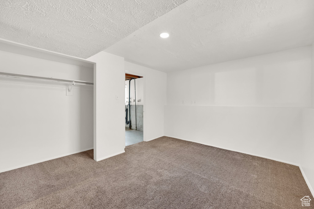 Unfurnished bedroom with a textured ceiling, carpet flooring, recessed lighting, and a closet