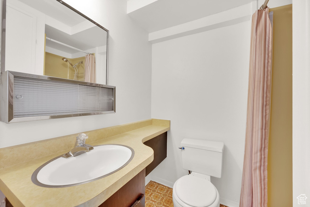 Bathroom featuring toilet, vanity, baseboards, and curtained shower