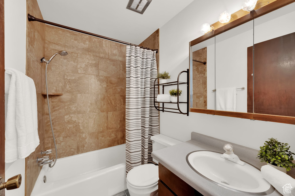 Full bathroom featuring shower / bath combo with shower curtain, vanity, and toilet