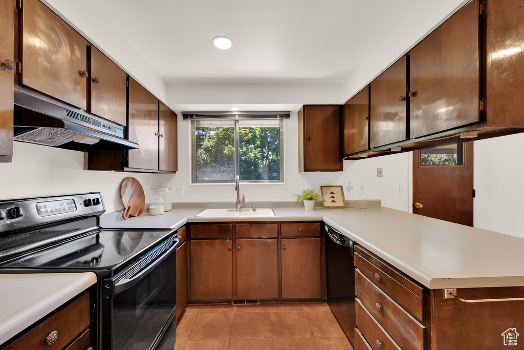 Kitchen featuring electric range, under cabinet range hood, a sink, black dishwasher, and light countertops