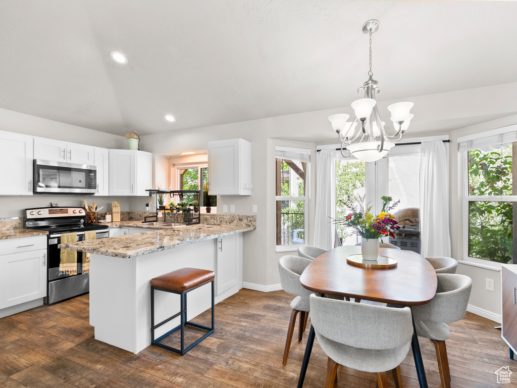 Kitchen with stainless steel appliances, a chandelier, white cabinetry, a peninsula, and dark wood-type flooring