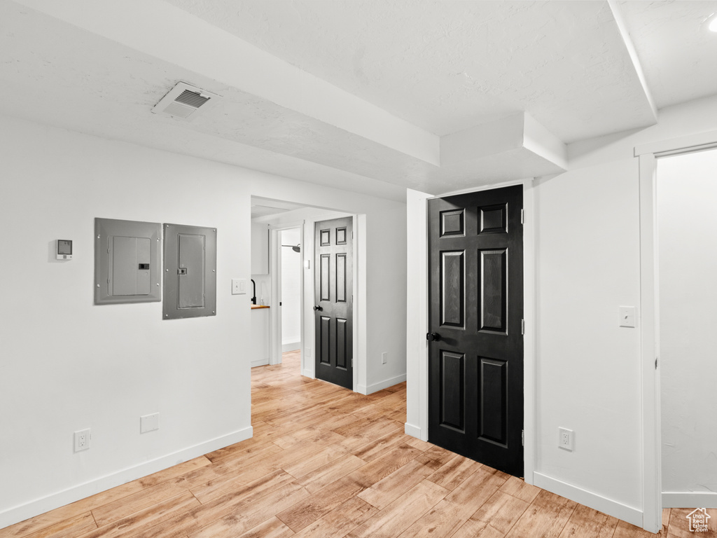 Empty room featuring electric panel, baseboards, and light wood-style floors