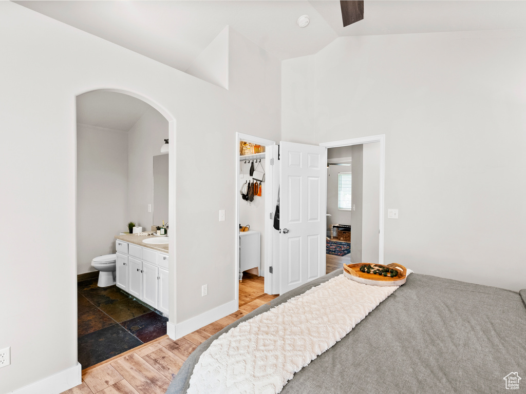 Bedroom with arched walkways, a spacious closet, a sink, ensuite bathroom, and wood finished floors