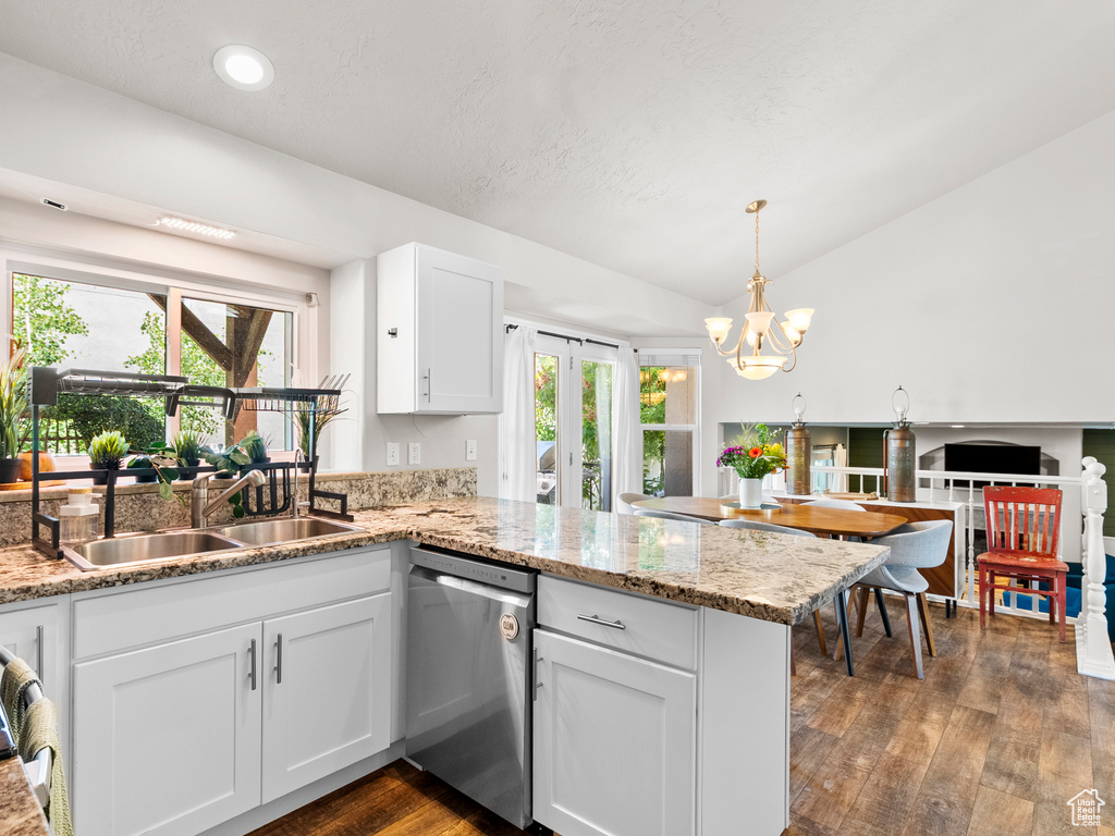 Kitchen with stainless steel dishwasher, a sink, a peninsula, dark wood-style floors, and white cabinetry