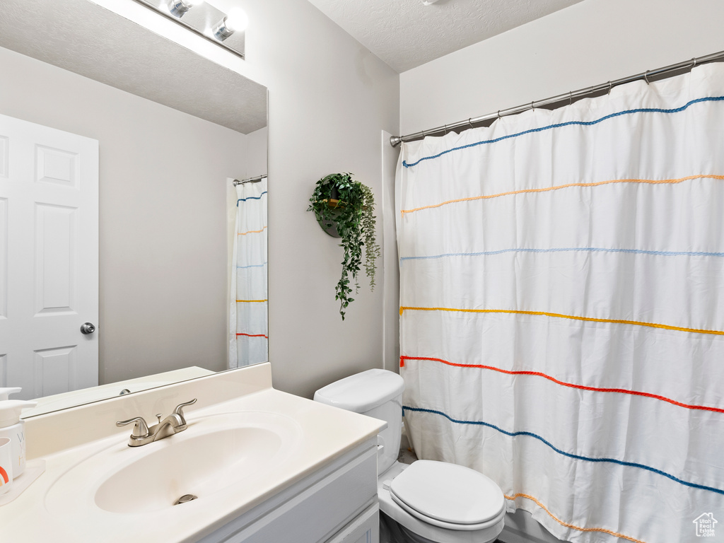 Bathroom with vanity, toilet, a textured ceiling, and a shower with curtain