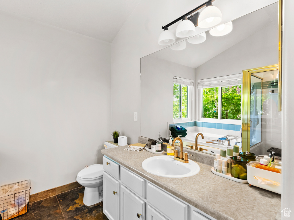 Bathroom with lofted ceiling, a shower stall, toilet, baseboards, and stone tile flooring
