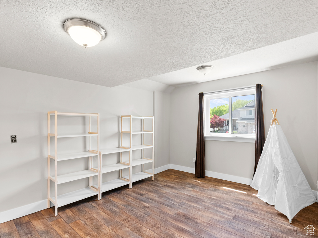 Bedroom with wood finished floors, baseboards, and a textured ceiling