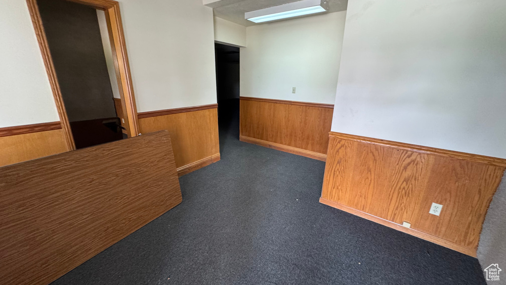 Unfurnished room featuring wainscoting, wooden walls, and carpet