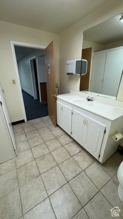 Bathroom with vanity, tile patterned floors, toilet, and a textured ceiling