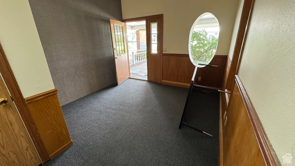 Foyer with a wainscoted wall, wood walls, and a textured wall