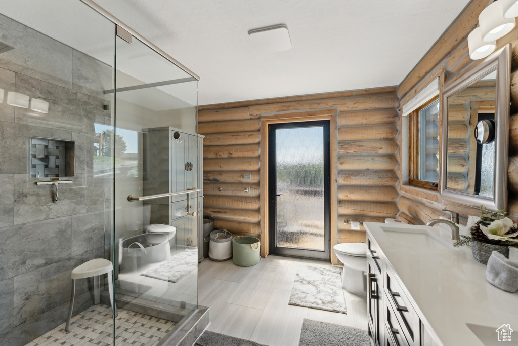 Bathroom featuring log walls, toilet, double vanity, and a shower stall