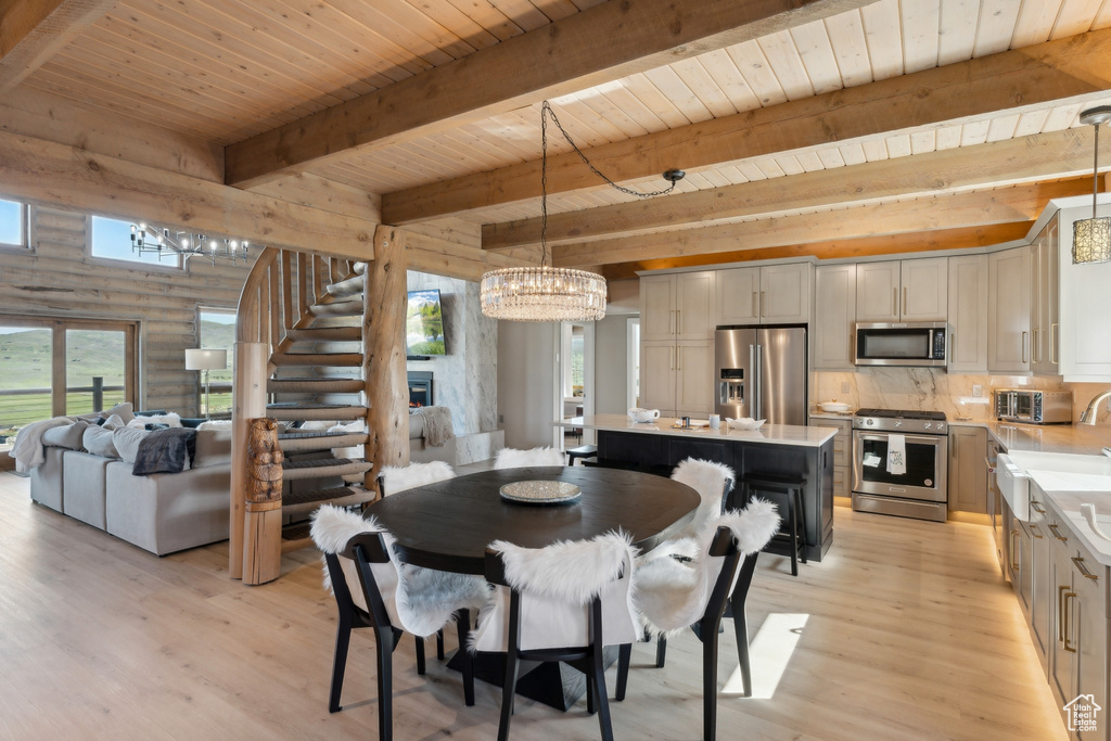 Dining area featuring light wood-style flooring, wood ceiling with exposed beams, stairs, a chandelier, and rustic walls