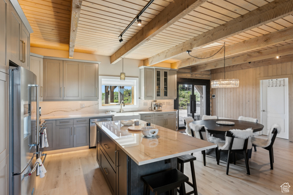 Kitchen featuring stainless steel appliances, light wood-style floors, decorative backsplash, light stone countertops, and wooden walls