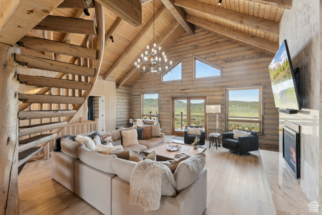 Living room featuring wood ceiling with exposed beams, high vaulted ceiling, light wood-style floors, a high end fireplace, and log walls