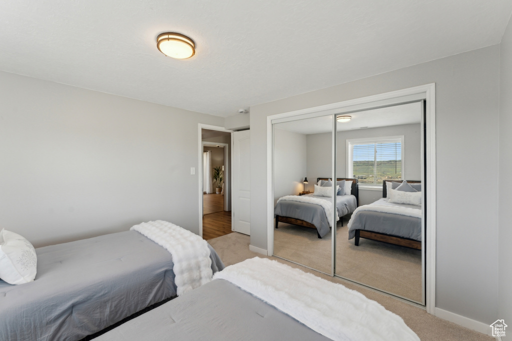 Bedroom with light carpet, a closet, and baseboards