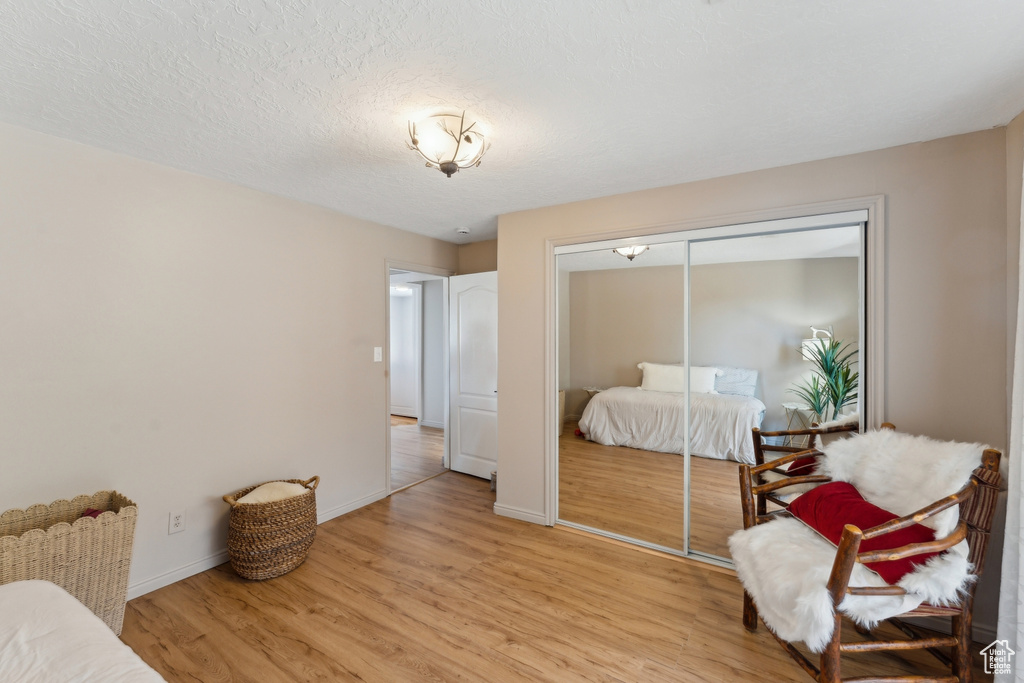 Bedroom with light wood finished floors, a closet, baseboards, and a textured ceiling