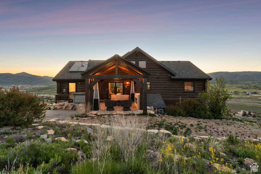 Cabin featuring an outdoor living space, log exterior, roof mounted solar panels, and roof with shingles