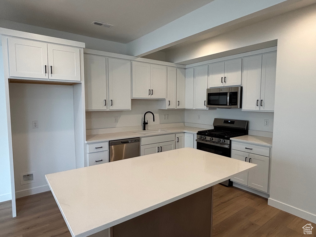 Kitchen with appliances with stainless steel finishes, a sink, baseboards, dark wood-style flooring, and beam ceiling