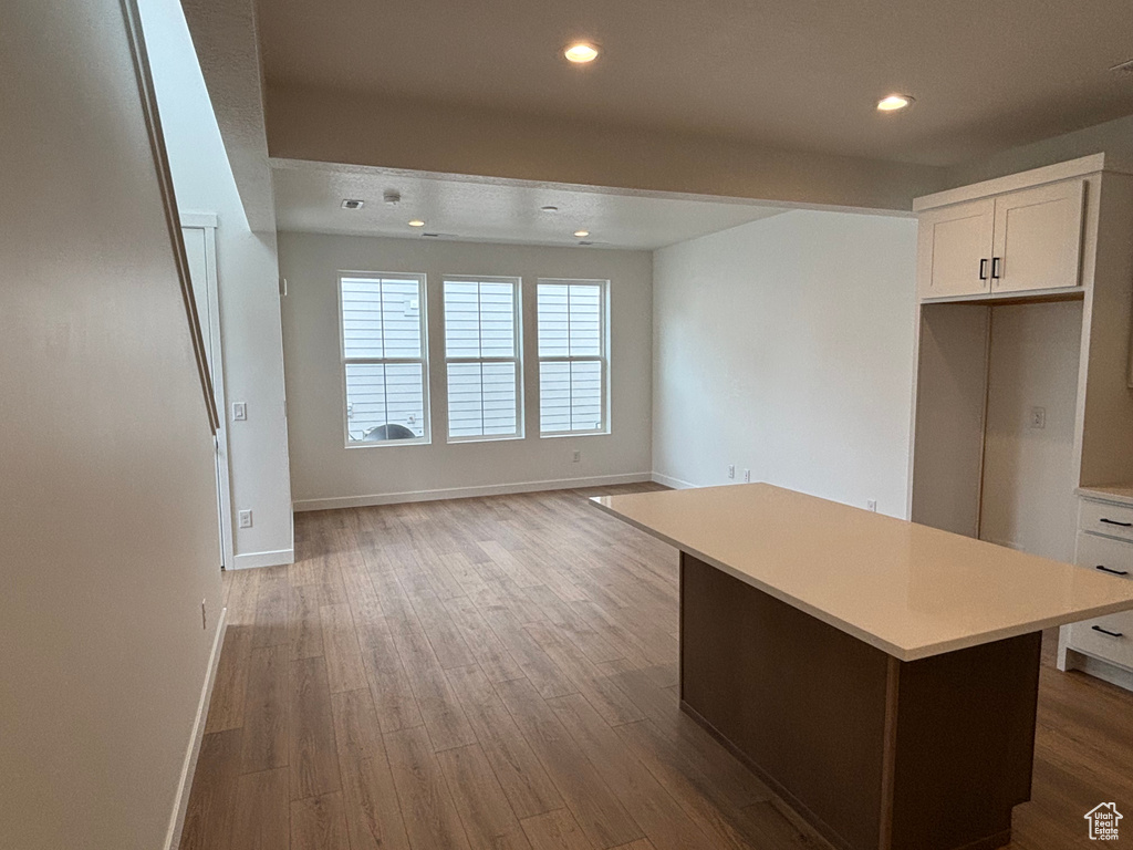 Kitchen with baseboards, light countertops, wood finished floors, and recessed lighting