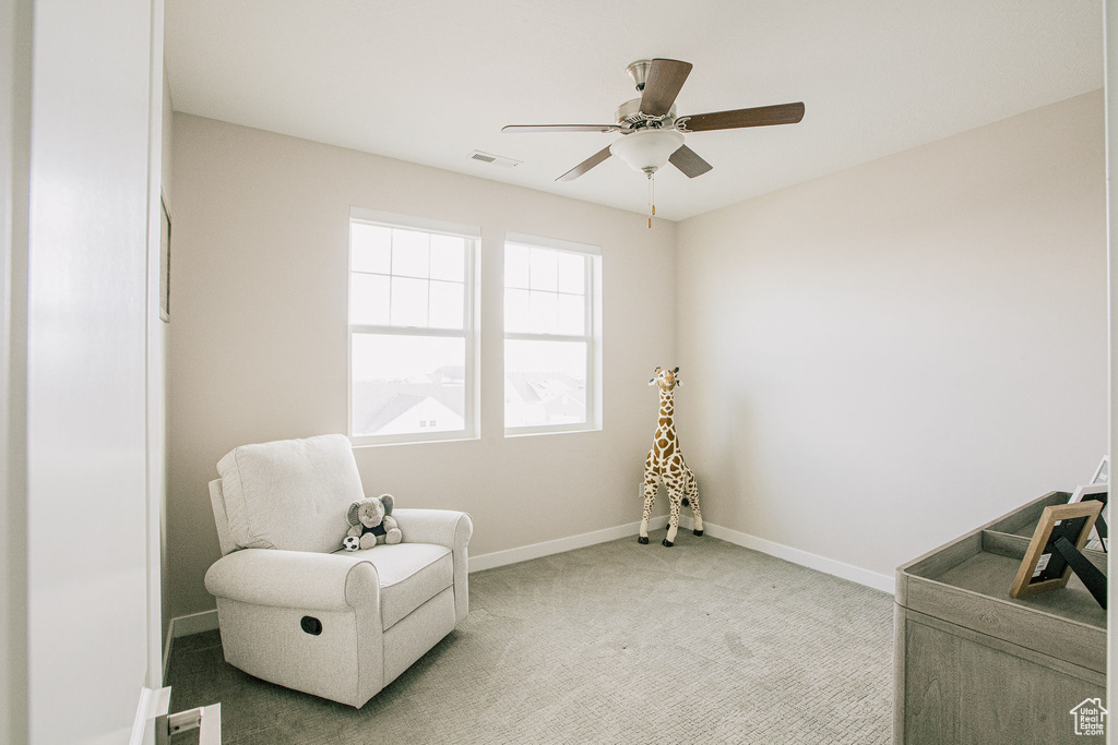 Sitting room featuring baseboards, light carpet, and a ceiling fan