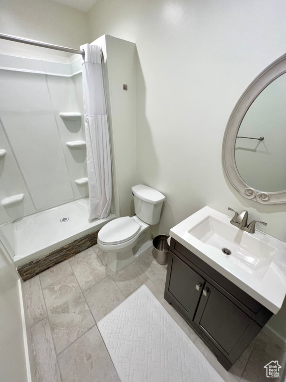 Bathroom featuring toilet, vanity, and a shower with shower curtain
