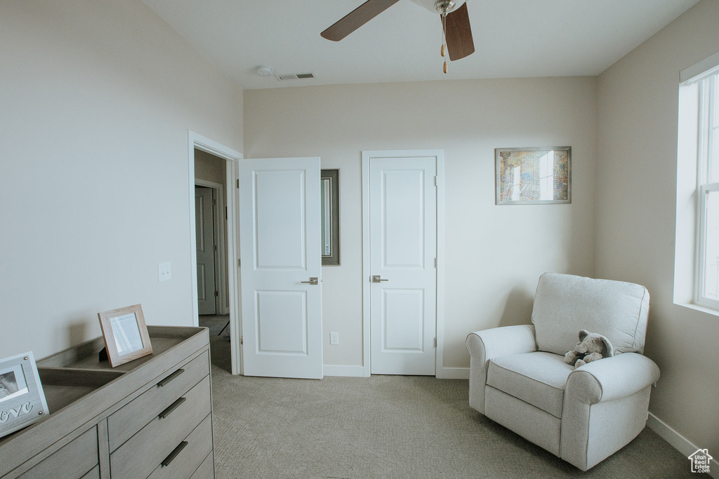 Living area featuring light colored carpet, a ceiling fan, and baseboards