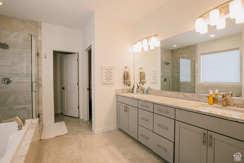 Bathroom featuring double vanity, a shower stall, a relaxing tiled tub, baseboards, and recessed lighting