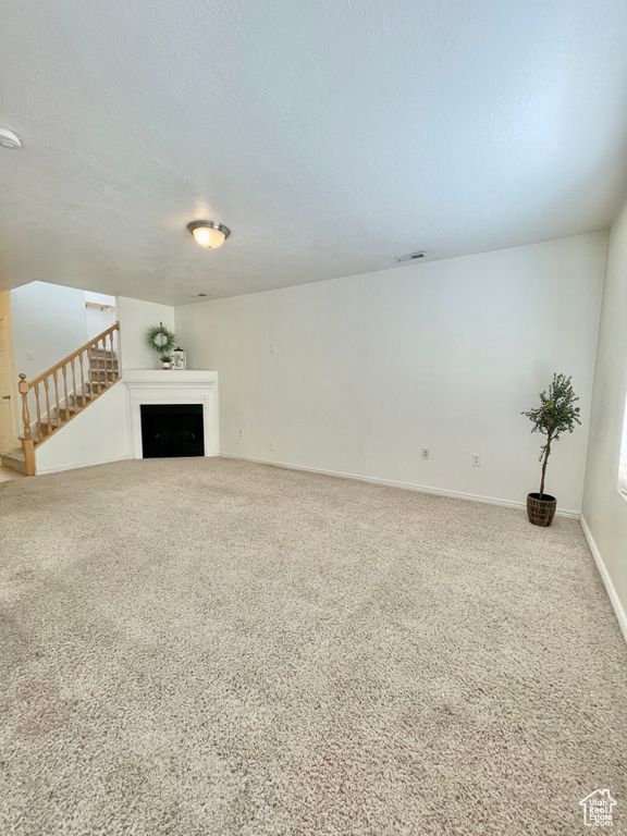Unfurnished living room with carpet flooring and a textured ceiling