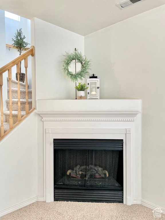 Detailed view of carpet flooring, a fireplace, and baseboards