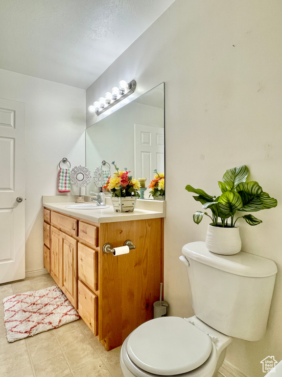 Half bath featuring vanity, tile patterned flooring, and toilet