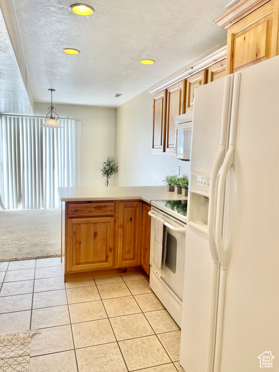 Kitchen featuring white appliances, a peninsula, light tile patterned floors, a textured ceiling, and light countertops