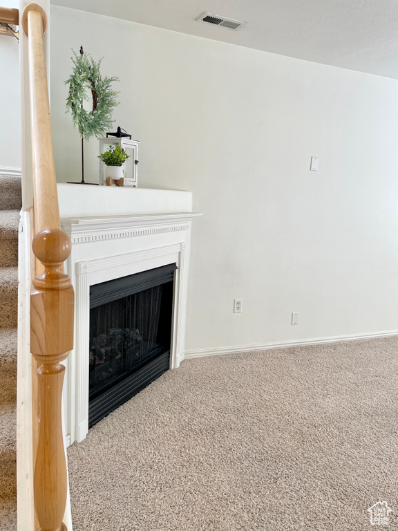 Unfurnished living room featuring carpet floors, a fireplace, and baseboards