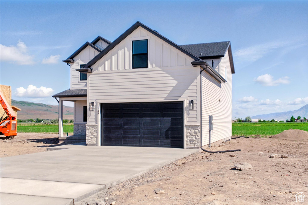 View of side of property with board and batten siding, driveway, an attached garage, and a mountain view
