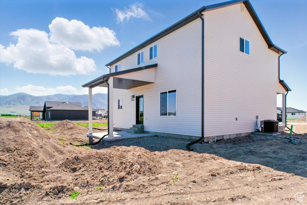 Rear view of property with a mountain view and central AC