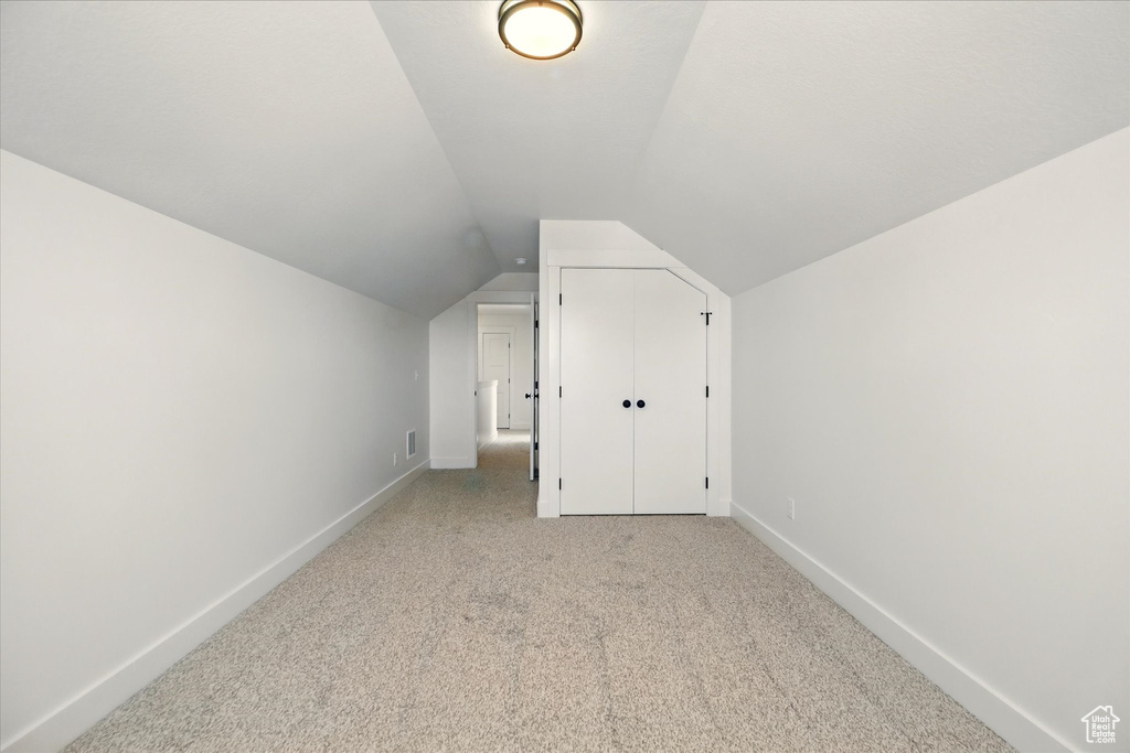 Additional living space with vaulted ceiling, light carpet, and baseboards