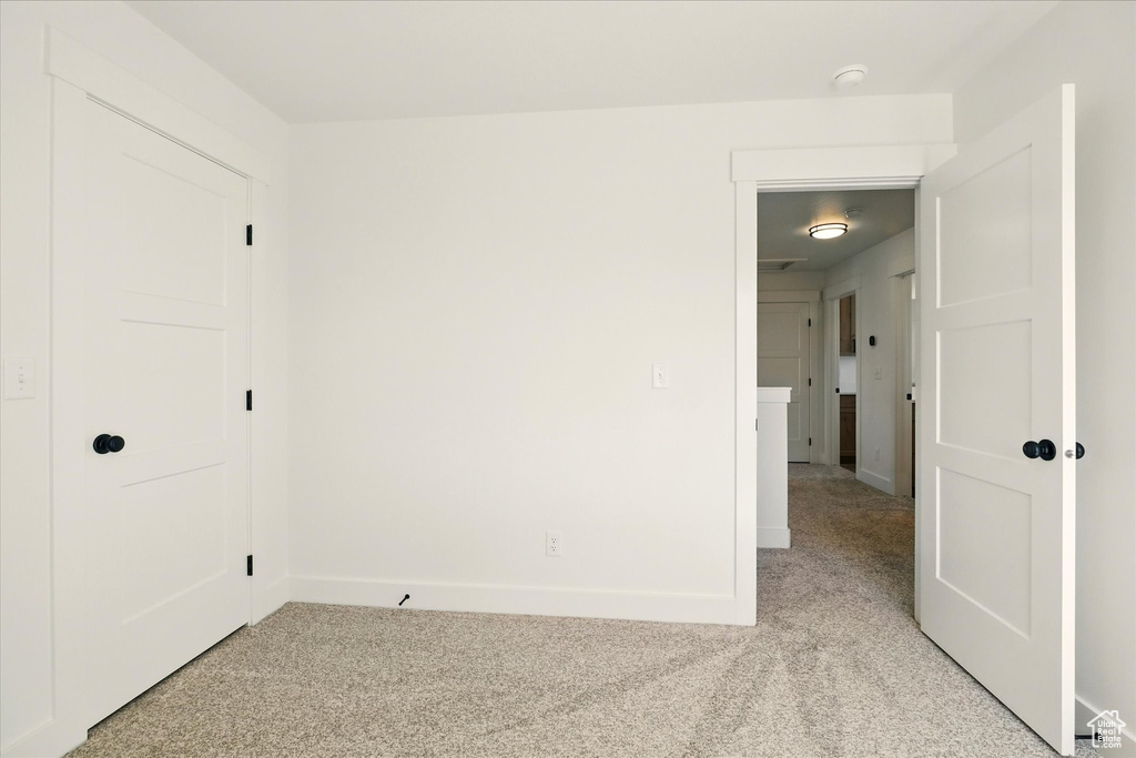 Unfurnished bedroom featuring light colored carpet and baseboards
