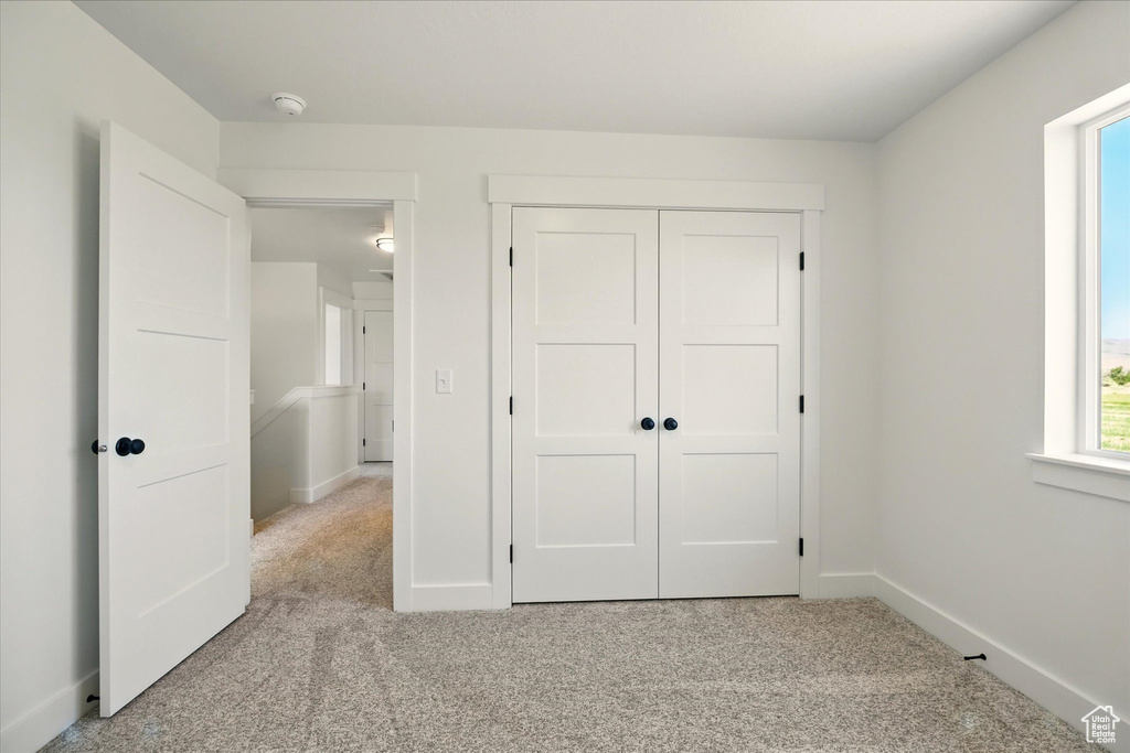 Unfurnished bedroom with carpet floors, baseboards, and a closet