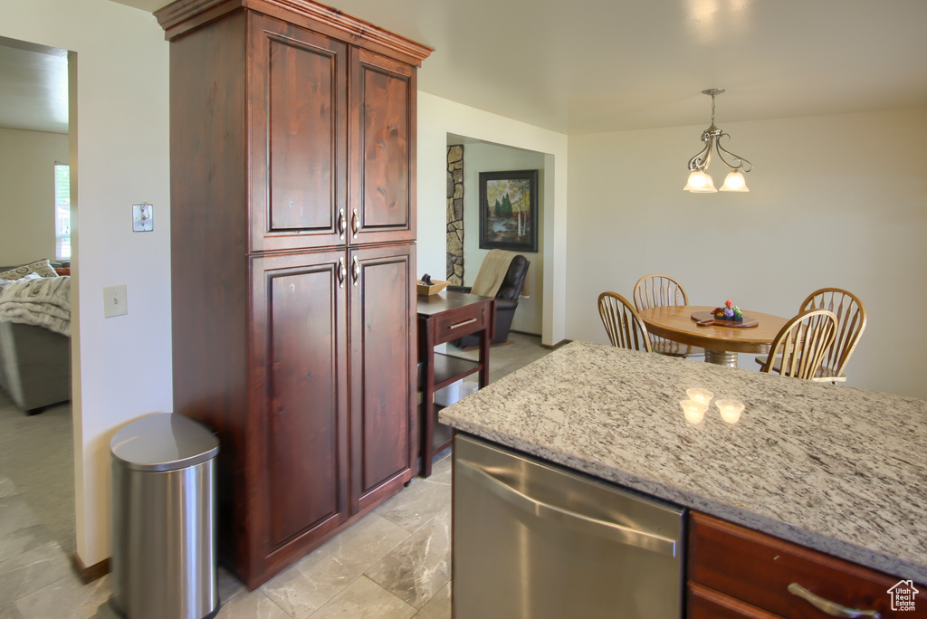 Kitchen featuring stainless steel dishwasher, reddish brown cabinets, and pendant lighting