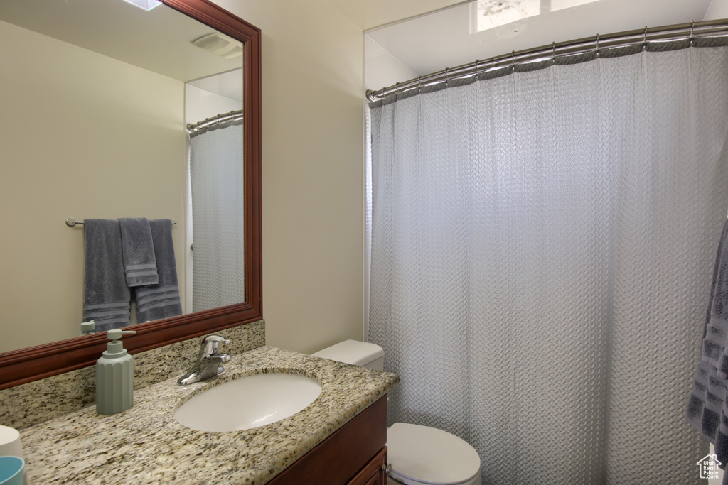 Bathroom featuring toilet, vanity, and a shower with curtain