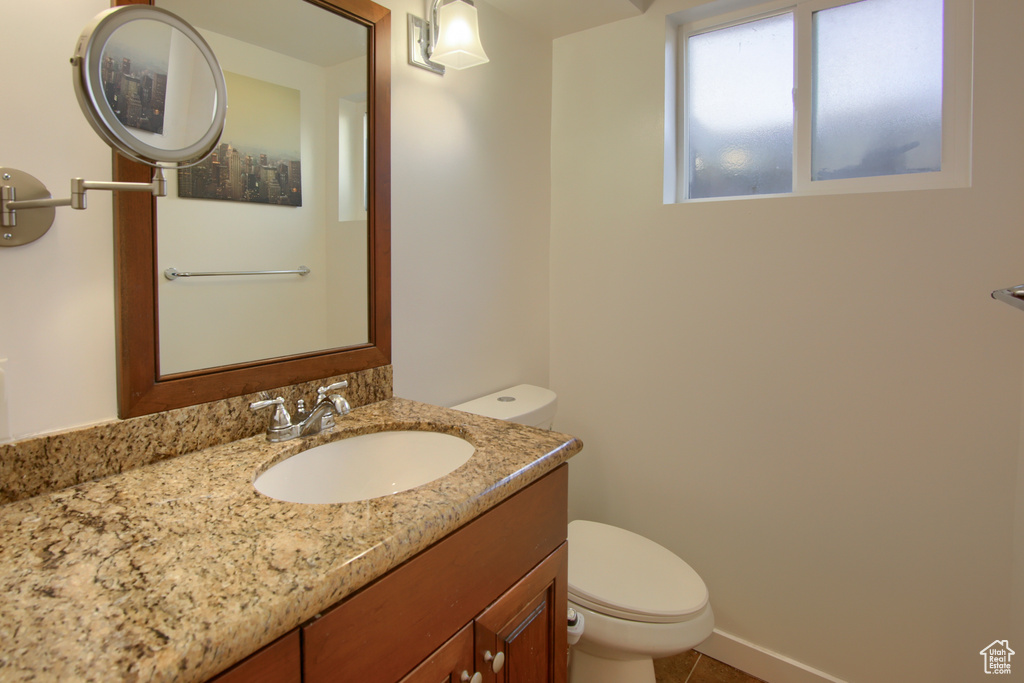 Bathroom with toilet, vanity, and tile patterned flooring