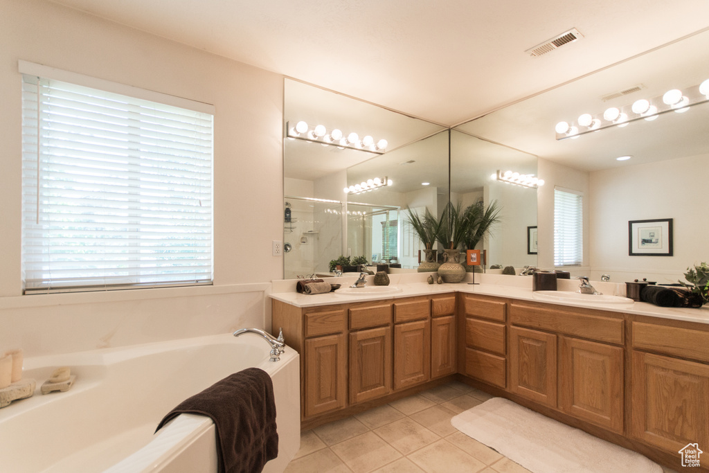 Full bath featuring a shower stall, tile patterned flooring, a garden tub, double vanity, and healthy amount of natural light