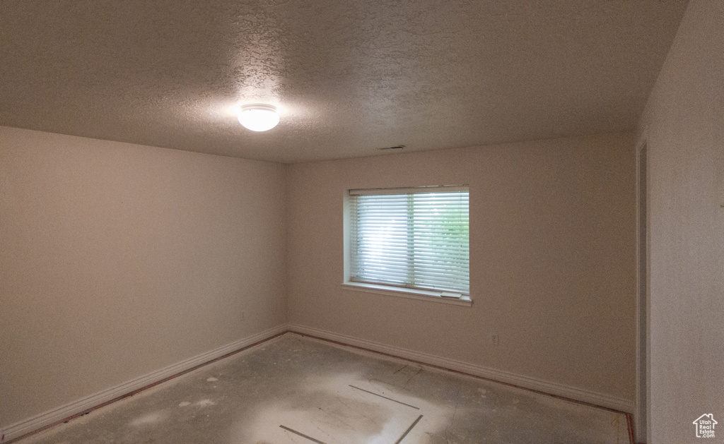 Empty room featuring baseboards and a textured ceiling