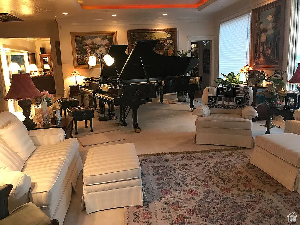 Carpeted living room with a raised ceiling, recessed lighting, and crown molding